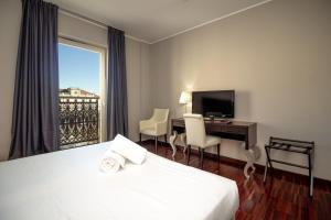 a hotel room with a bed and a desk and a window at Hotel Cavour in Novara