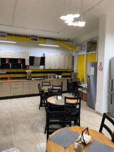 a restaurant with tables and chairs and a kitchen at Uley Hostel in Krasnogorsk