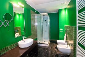 a green bathroom with two sinks and a shower at Hotel Cavour in Novara
