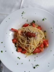 a white plate of pasta with tomatoes and sauce at Hotel Verdesolemare in Marina di Pietrasanta