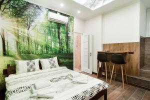 a bedroom with a bed and a painting of a forest at Art Apartments on Deribasovskaya in Odesa