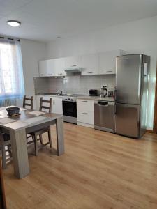 a kitchen with a table and a stainless steel refrigerator at Le Cyprès en centre ville Bourg-Saint-Maurice in Bourg-Saint-Maurice