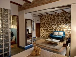 Habitación con sofá azul y pared de piedra. en Casa Rural La Rocha en Chulilla