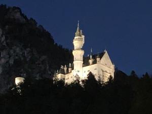 un château installé au sommet d'une montagne la nuit dans l'établissement Hotel Fischer am See, à Füssen
