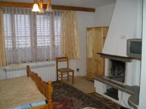 a living room with a fireplace and a chair at Damianka Guest House in Bansko