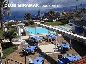 una piscina con tavoli e sedie blu accanto a un edificio di CHALET ADOSADO CON TERRAZA Y AZOTEA a Los Realejos