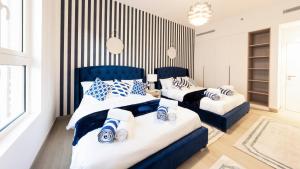 Duas camas com almofadas azuis e brancas num quarto em Ultimate Stay - 4 Beds - La Mer - Sunset Marina View em Dubai