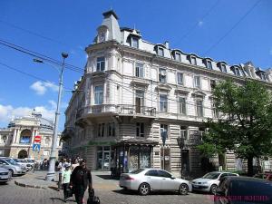 een groot wit gebouw in een stadsstraat met auto's bij Art Apartments on Deribasobskaya in Odessa