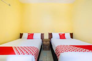 2 camas en una habitación con sábanas rojas y blancas en OYO Hotel Y Restaurante Mitla, Oaxaca, en San Pablo Villa de Mitla