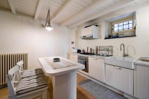 a kitchen with white cabinets and a sink and a table at Residenza Stoechas in Albenga