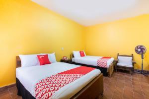 two beds in a room with yellow walls at OYO Hotel Y Restaurante Mitla, Oaxaca in San Pablo Villa de Mitla