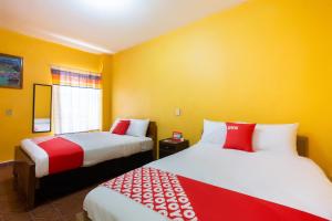 two beds in a room with yellow walls at OYO Hotel Y Restaurante Mitla, Oaxaca in San Pablo Villa de Mitla