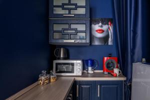 a kitchen with blue walls and a counter with a microwave at Romantika Smolny appartment in Saint Petersburg