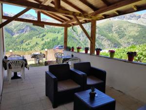 un patio con sillas, mesas y montañas de fondo en Õ 2040 Chambre Marmotte, en Saint-Véran