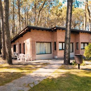 a brick house with a patio in the woods at La Mansion del Bosque in Mar de las Pampas