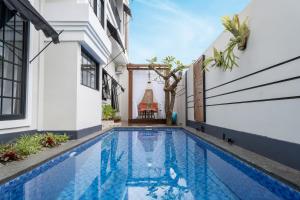 a swimming pool in the courtyard of a house with a building at Hening Pool Villa in Purwokerto