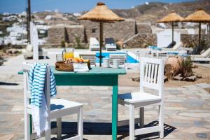 a table with a basket of fruit and two chairs at Amperian Mykonos Suites & Villas in Mikonos