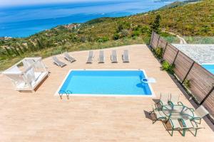 a swimming pool with chairs and a view of the ocean at Villa Stephania in Orthoniaí