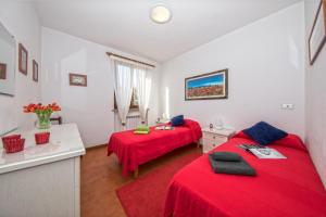 two beds in a room with red sheets at Residence Edera 18 by Wonderful Italy in Polpenazze del Garda