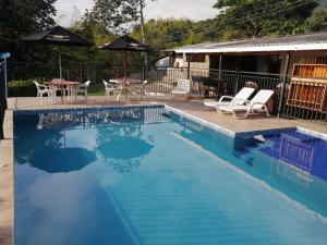 a swimming pool with chairs and tables next to a house at FINCA LA RAMONA in El Pomo