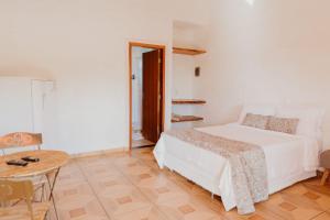 a white bedroom with a bed and a table at Pousada Cafune in Socorro