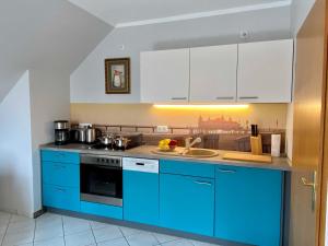 a kitchen with blue cabinets and a sink at Ferienappartements Mund - Adults only in Gothen