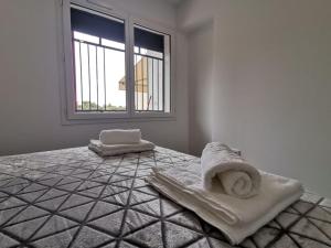 a white room with a bed with towels on it at Canyelles BBQ Apartment in Lloret de Mar