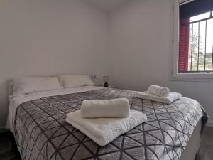 a white bedroom with a bed with towels on it at Canyelles BBQ Apartment in Lloret de Mar