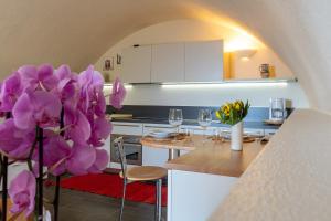 a kitchen with a table with purple flowers at Casa di campagna Tony con piscina e vista lago in Gravedona +13 photos