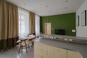 - un salon avec des murs verts, une table et des chaises dans l'établissement Ruterra Apartment Charles Bridge, à Prague
