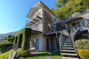 a house with stairs leading up to a building at Casa di campagna Tony con piscina e vista lago in Gravedona