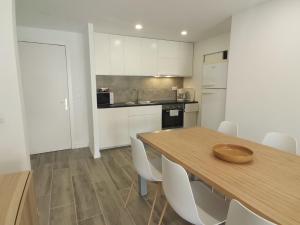 a kitchen with a wooden table and white cabinets at Canyelles BBQ Apartment in Lloret de Mar