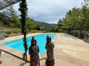two statues standing in front of a swimming pool at Gîte "Bois-Mariage" in Mollans-sur-Ouvèze