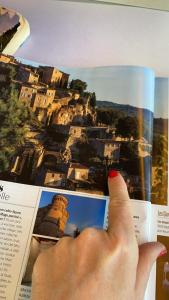 a hand holding a book with a picture of a city at Le Bonheur in Gordes