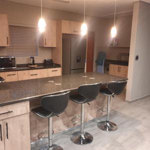 a kitchen with a counter with four bar stools at @Lloyds in Ermelo