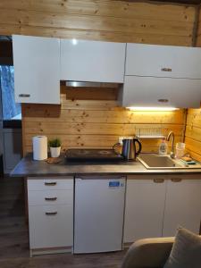 a kitchen with white cabinets and a sink at Domek SERCE KRYNICY in Krynica Morska