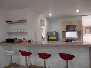 a kitchen with red bar stools at a counter at Edificio Reserva del Mar, Paya Salguero , Santa marta in Gaira