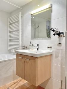 La salle de bains est pourvue d'un lavabo, d'un miroir et d'une baignoire. dans l'établissement Ferienwohnung Kirchbichl am Schliersee mit Terrasse, à Schliersee