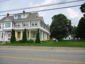 Casa blanca grande con porche en una calle en Governor's Mansion Inn, en Miramichi