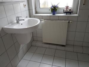 La salle de bains blanche est pourvue d'un lavabo et d'une fenêtre. dans l'établissement Darßer Weg 32a "Kormoran" Wohnung 16, à Zingst