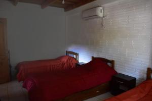 duas camas com lençóis vermelhos num quarto com uma parede em Casa Cumandai em San Javier