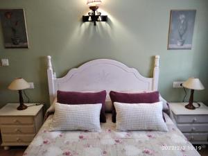 ブロンチャレスにあるCasa Rural Lahuertaのベッドルーム1室(白と紫の枕が付いた白いベッド1台付)