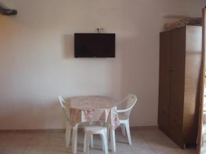 mesa con 2 sillas y TV en la pared en SKIATHOS STUDIOS, en Skiathos