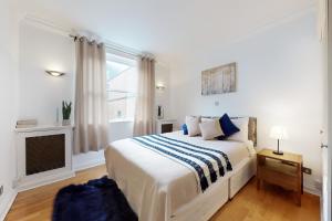 Dormitorio blanco con cama y chimenea en Stay in bond street, en Londres