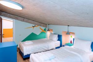two beds in a room with blue walls and a ceiling at Paliani Hostel in Mestia