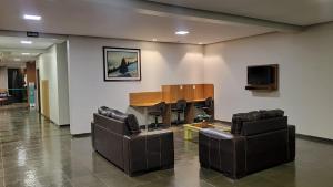 a waiting room with couches and a table and a television at Hotel das Acacias in São Sebastião do Paraíso