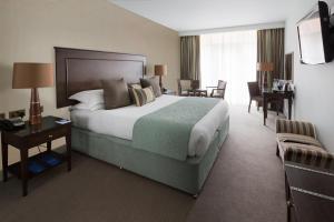 a hotel room with a large bed and a desk at The Oxfordshire Golf & Spa Hotel in Thame