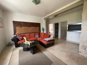 a living room with a red couch and a table at Gîte "Bois-Mariage" in Mollans-sur-Ouvèze