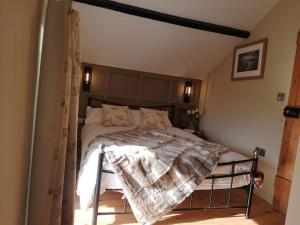 a bedroom with a bed with a blanket on it at Pentwyn Barn in Brynamman