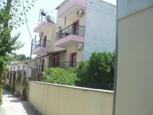 un edificio rosa y amarillo con balcones en una calle en SKIATHOS STUDIOS en Skíathos